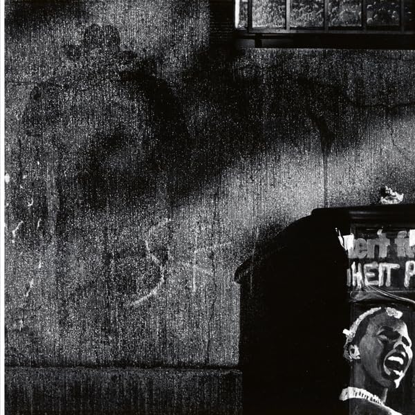 Black and white album cover with a shadowed figure and graffiti.