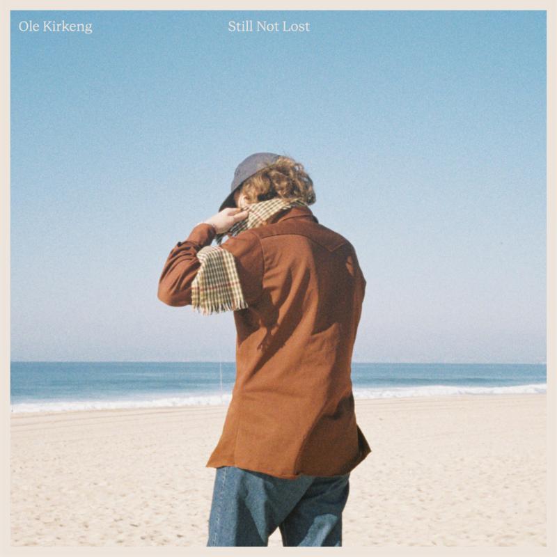 Album cover: man with back to viewer on a beach.