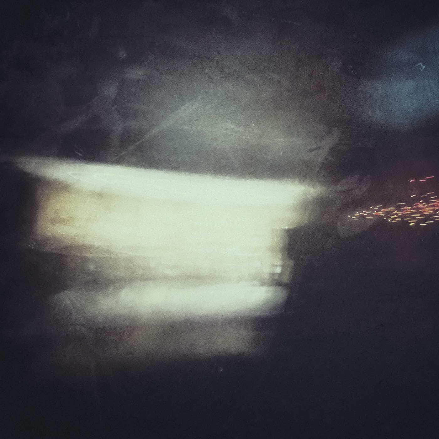Dark, abstract image with a blurred, glowing rectangular shape and red specks.
