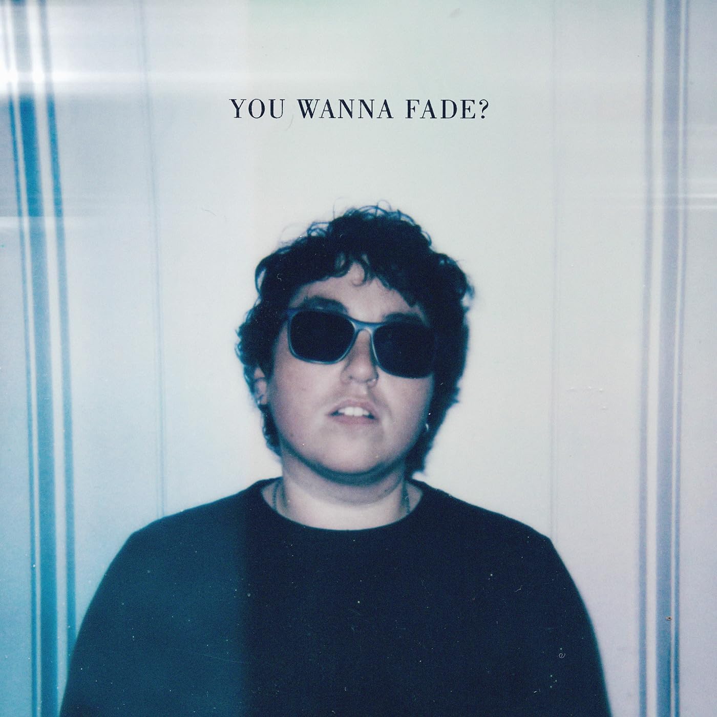 Portrait of a person with dark curly hair and sunglasses.