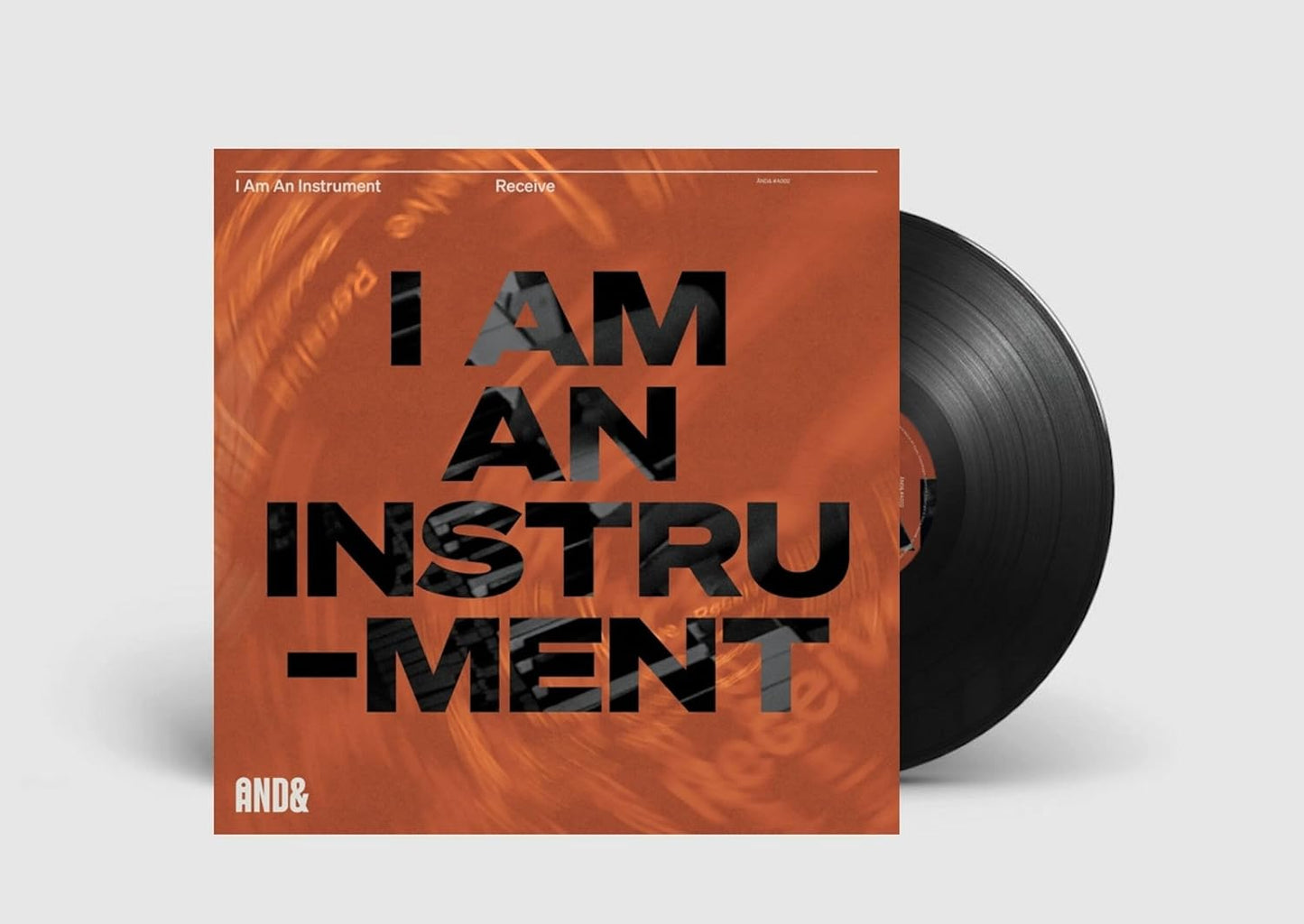 Vinyl record with bold text "I AM AN INSTRUMENT" and abstract orange design.