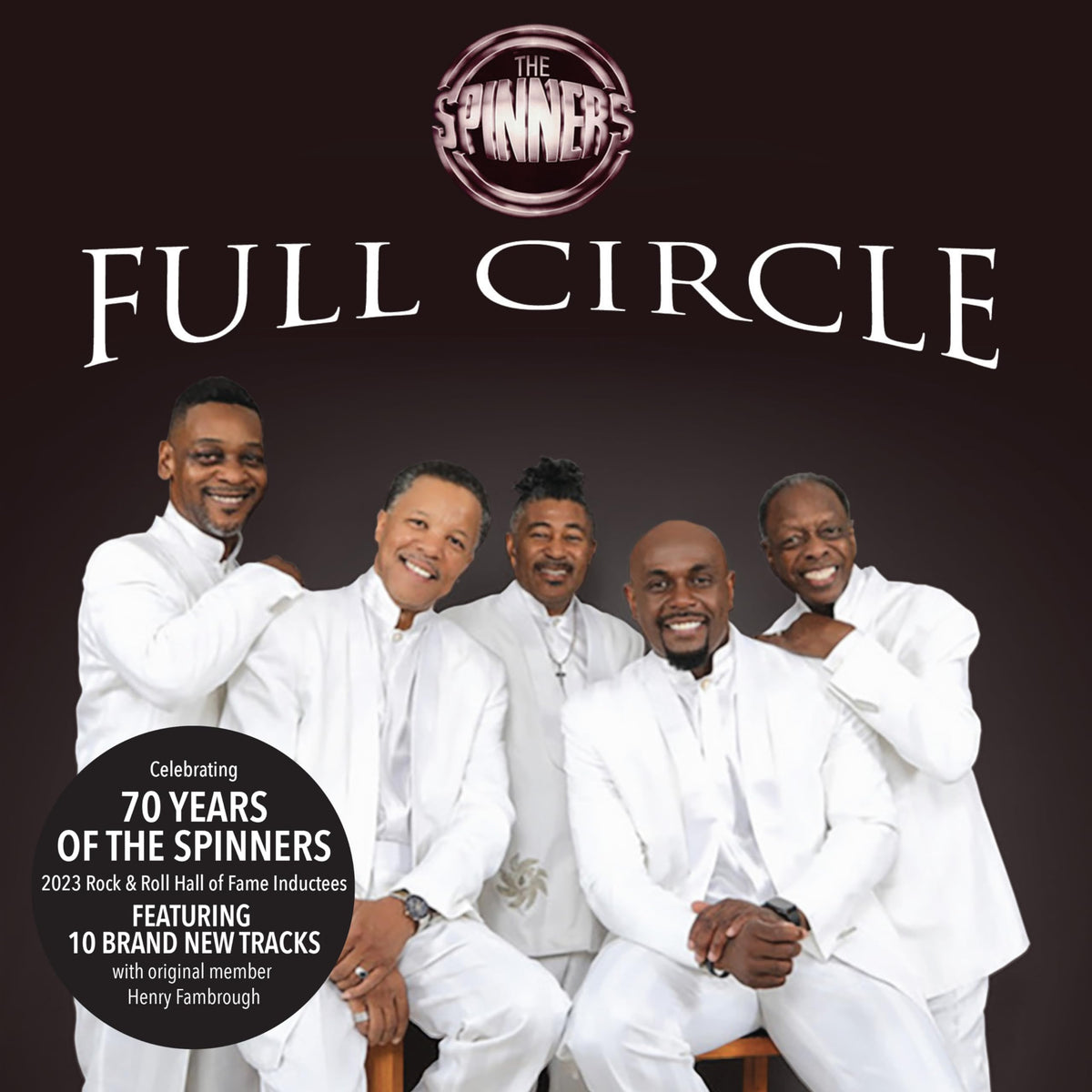 The Spinners, a group of five men in white suits, smiling at the camera.