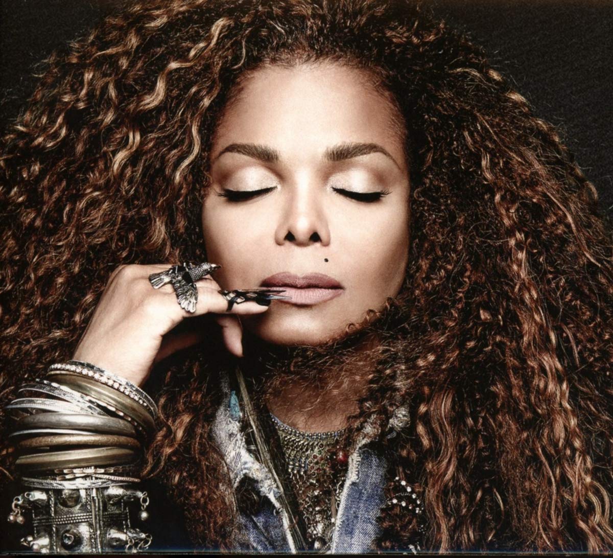 Janet Jackson with closed eyes, curly hair, and ornate jewelry.
