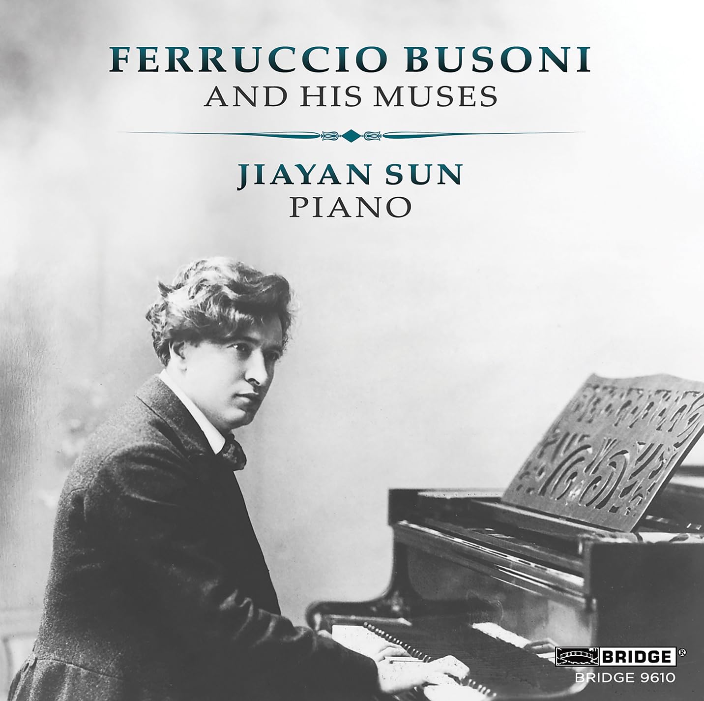 Black and white portrait of composer Ferruccio Busoni at a piano.