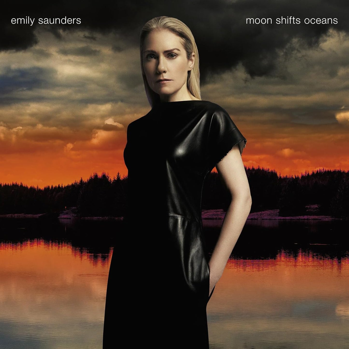 Woman in black dress stands before a fiery landscape and water.