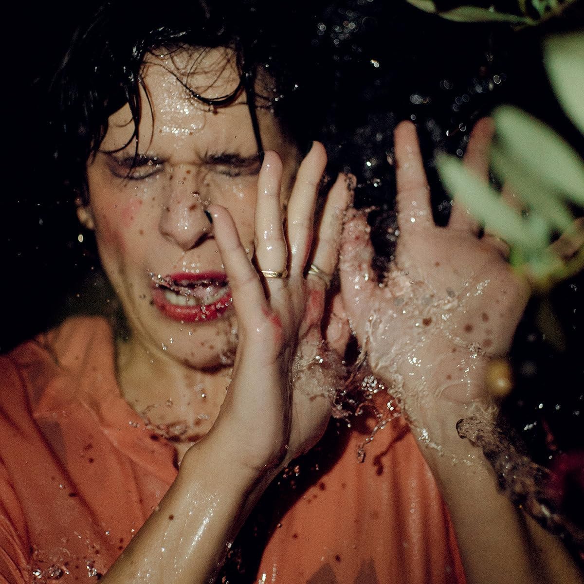 Person with wet hair and hands, water splashing on face.