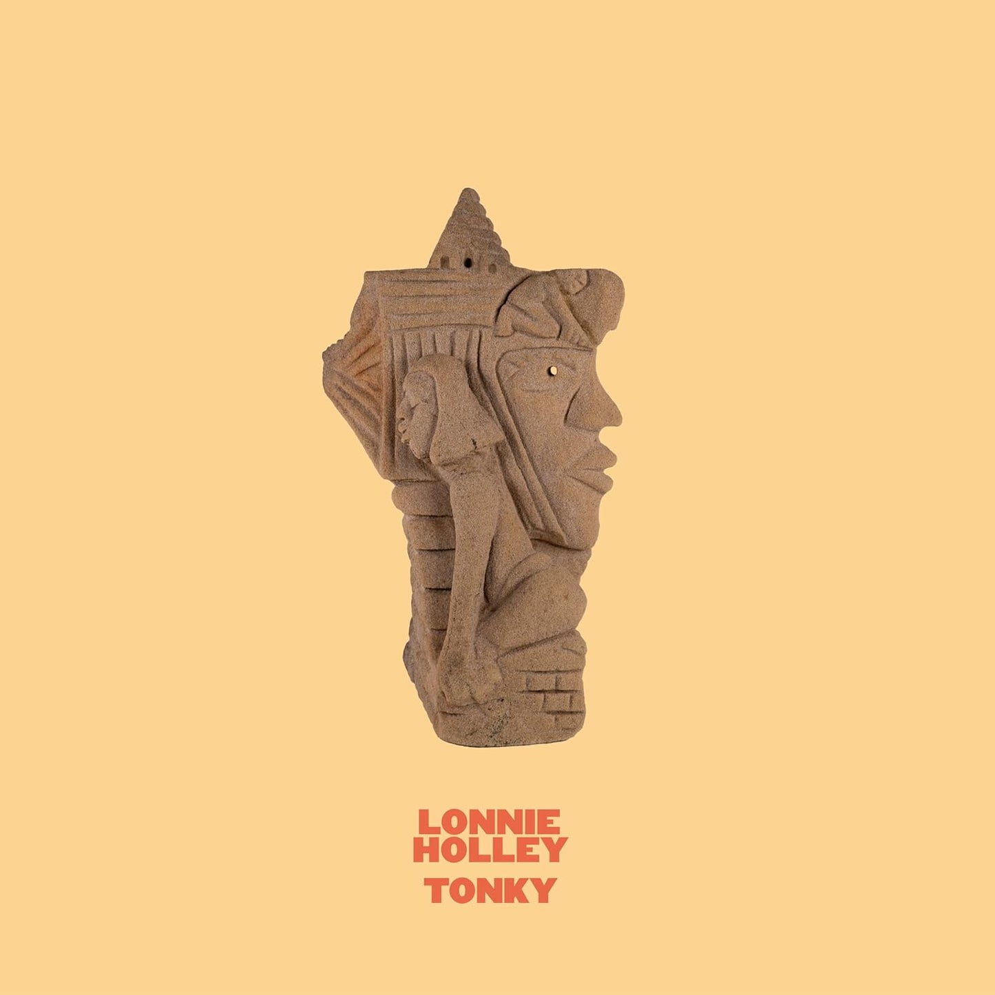 Vinyl record cover featuring a carved stone face on a yellow background.