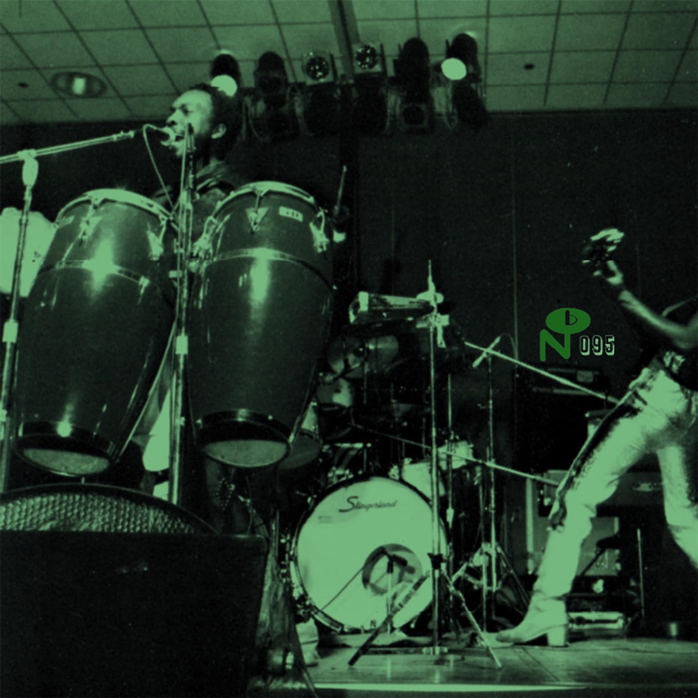 Black and white photo of a drummer and singer performing on stage.