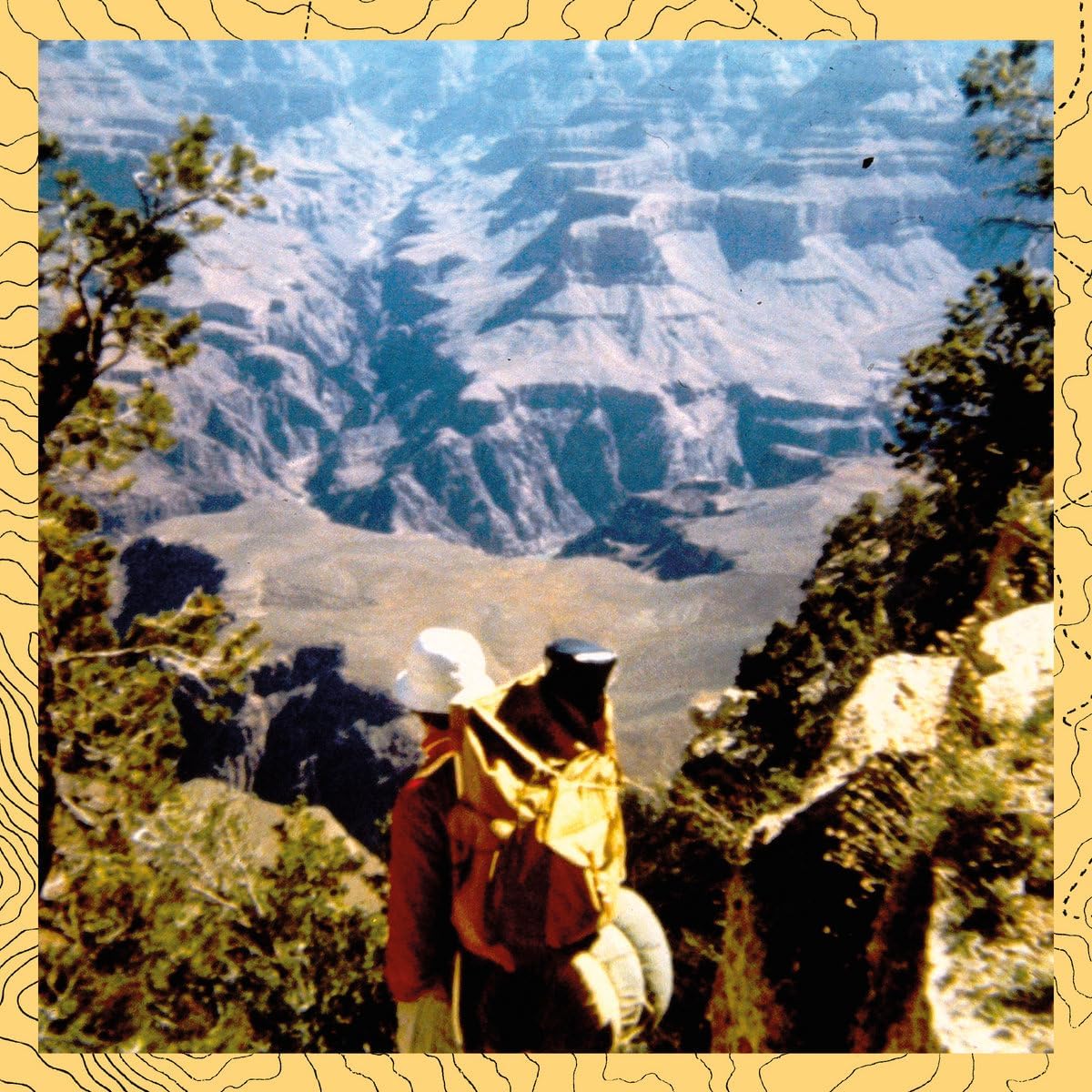 Person with backpack views a vast canyon landscape from a ridge.