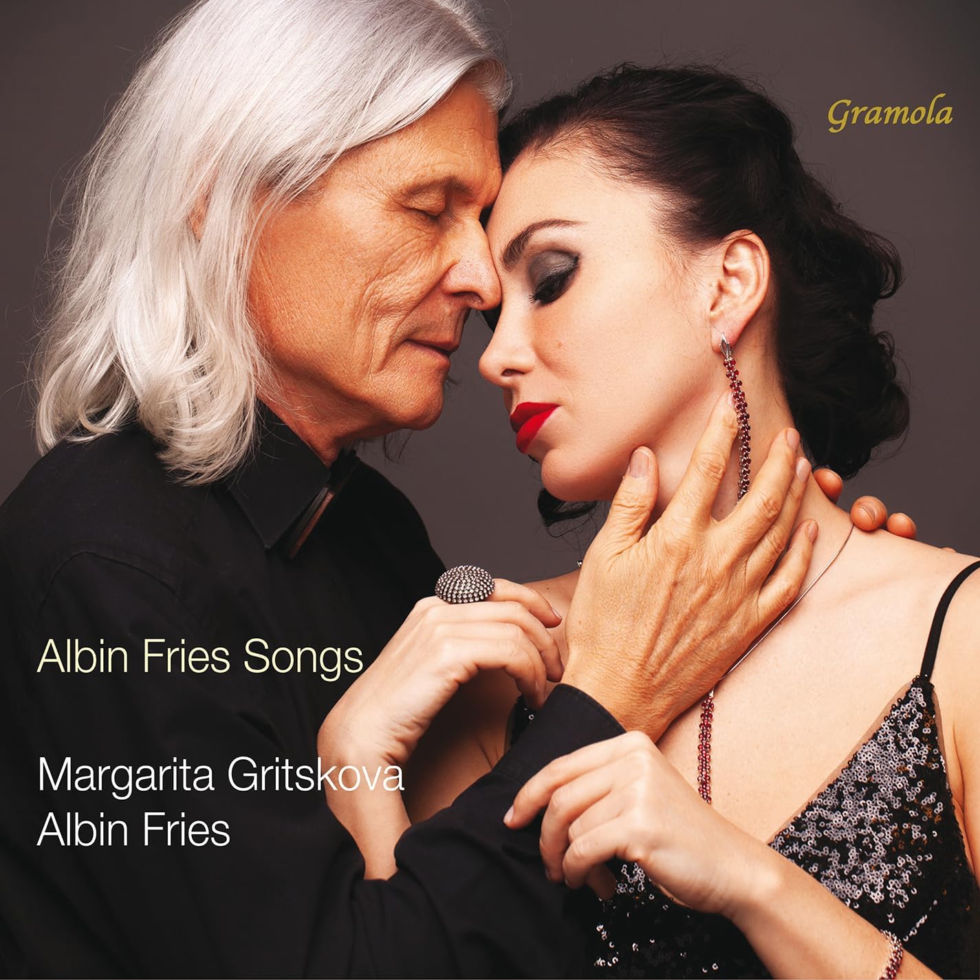 An older man with long white hair and a woman touching foreheads closely.