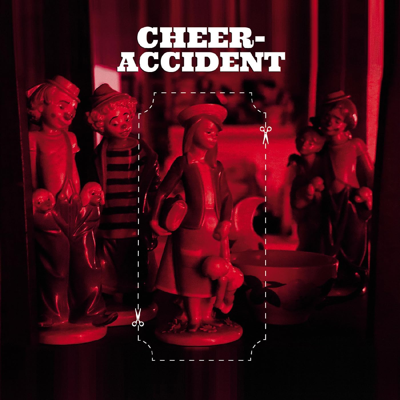 Red figurines arranged around a central, broken figure with scissors.