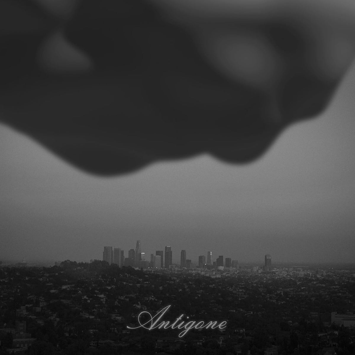 Black and white cityscape under a dark, cloudy sky; text “Antigone”.