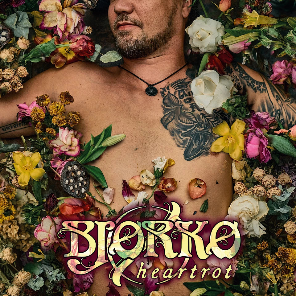 Bjorko album cover: shirtless man adorned with flowers and tattoos.