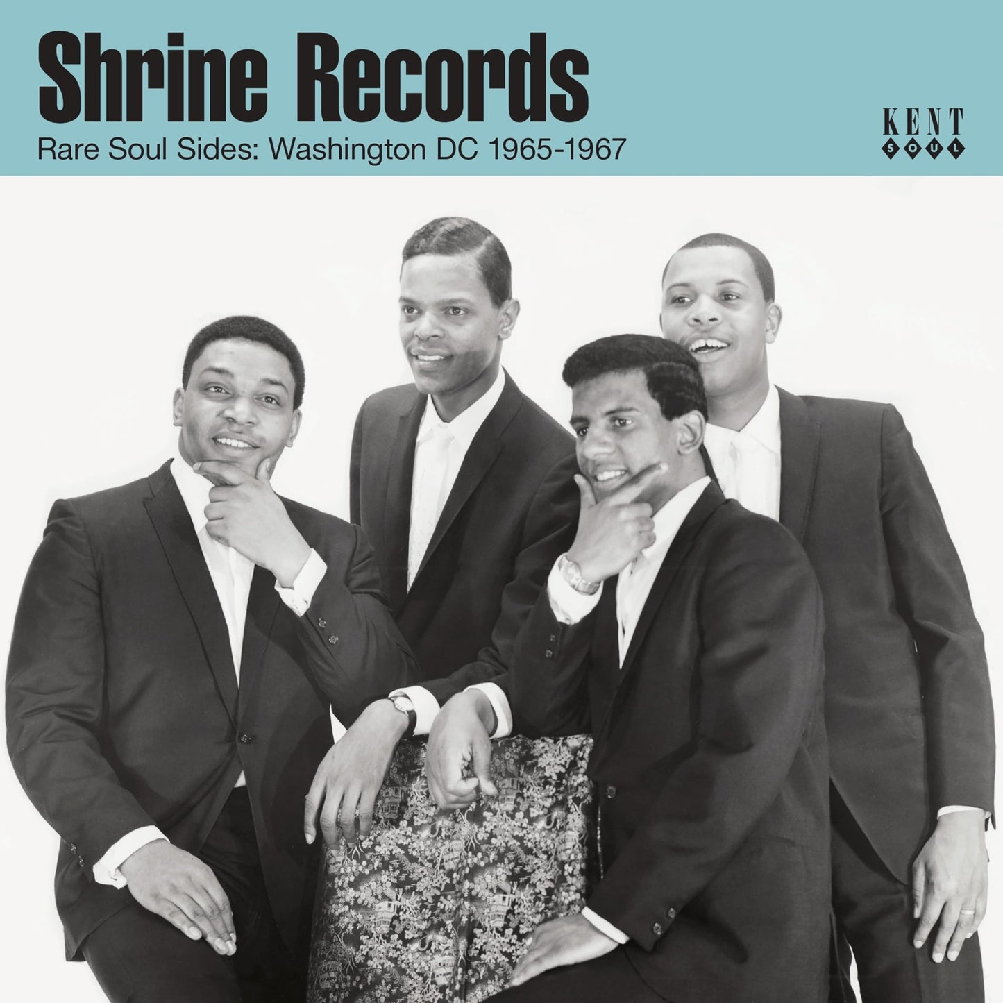 Black and white photo of four men in suits posing for a music album cover.