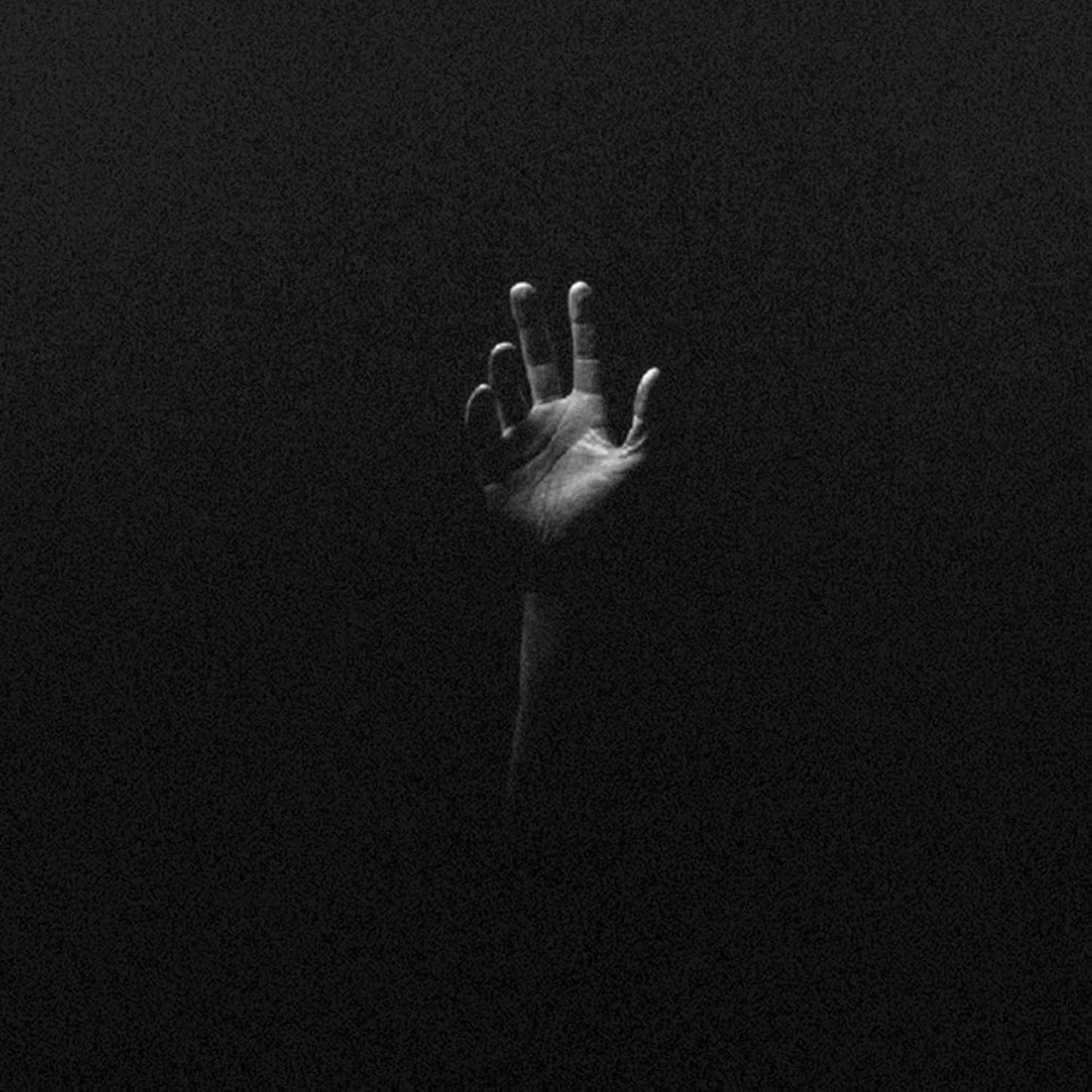 Black and white image of a hand reaching up from darkness.