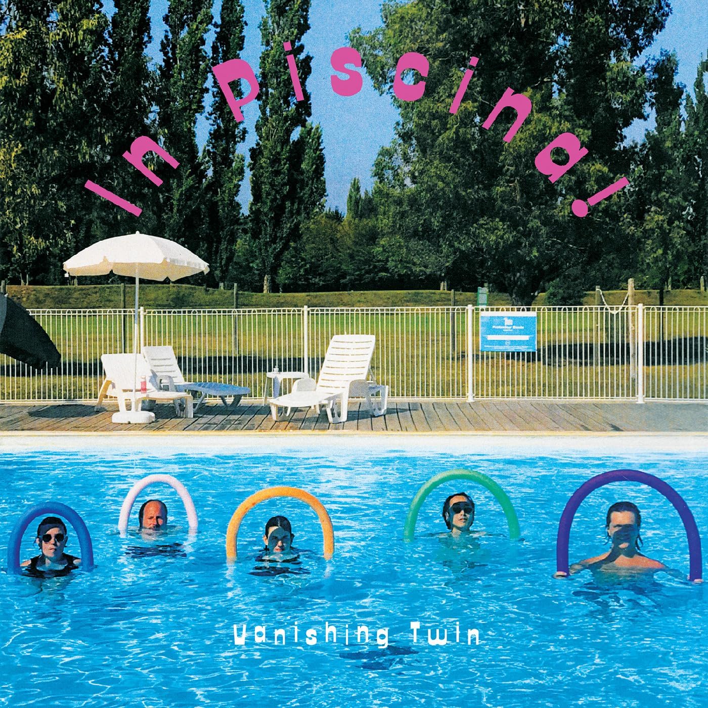 People in a blue swimming pool with colorful inflatable rings.
