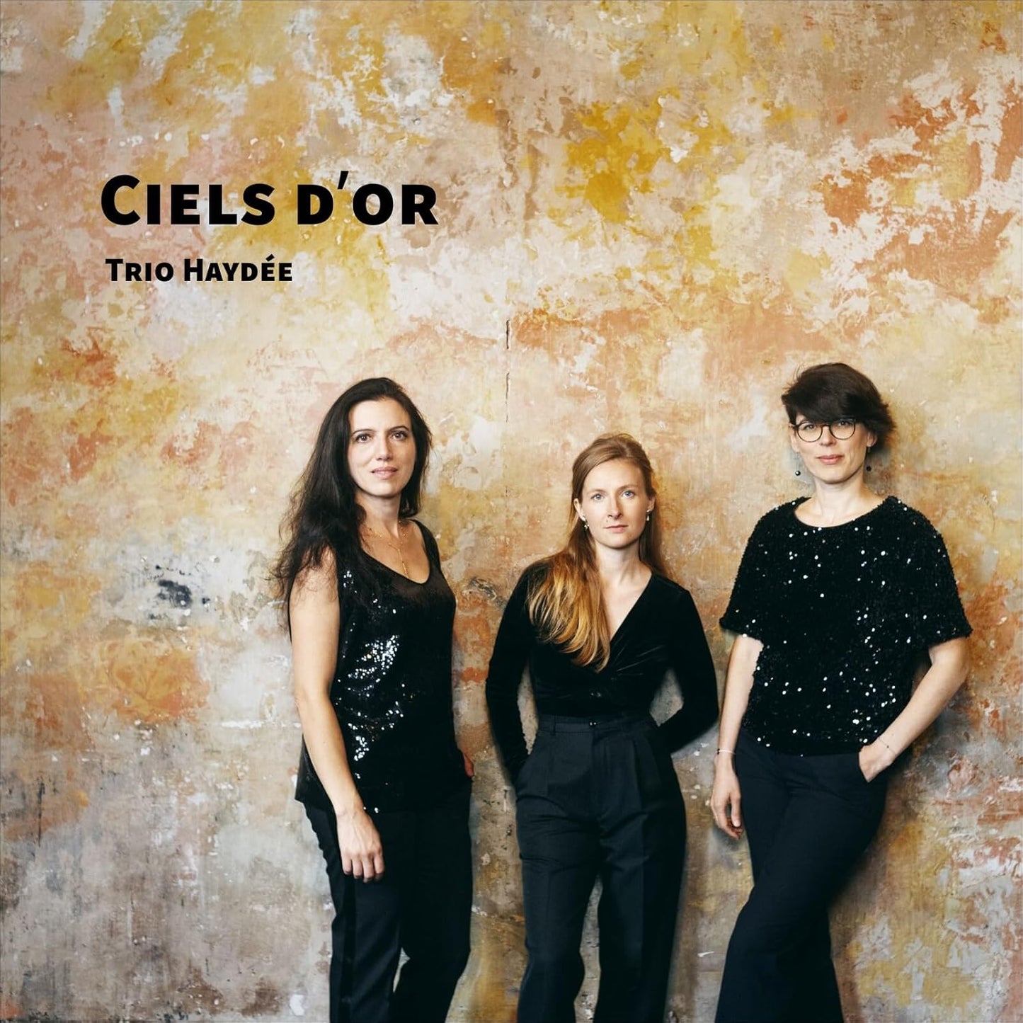 CD cover featuring three women in dark clothing against a textured gold background.