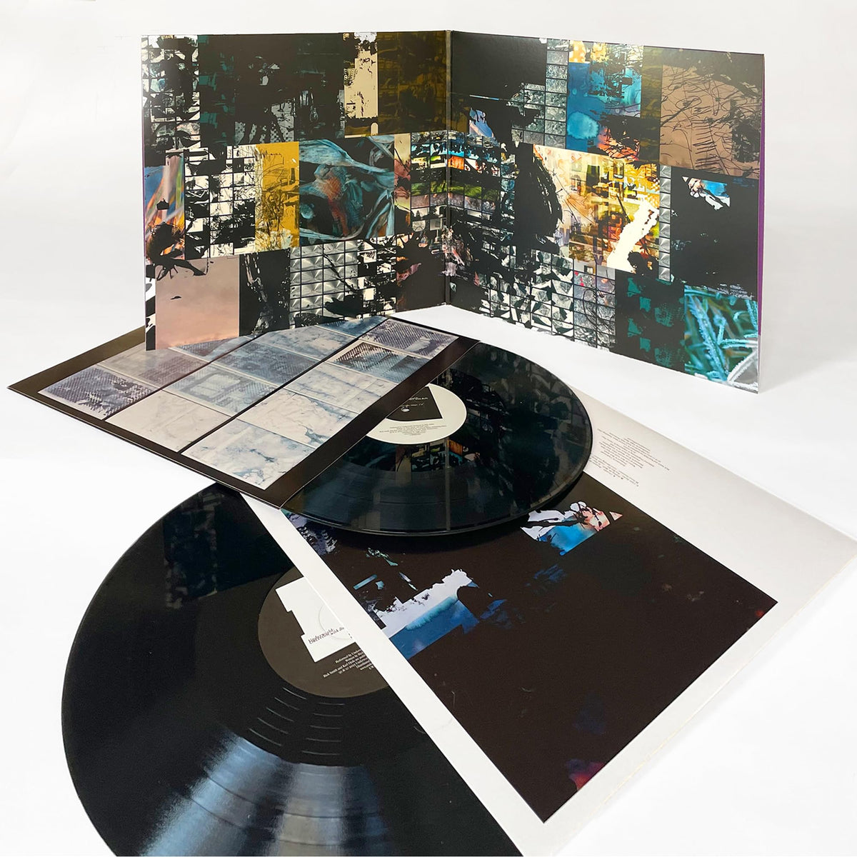 Open vinyl record with abstract, fragmented collage album artwork.