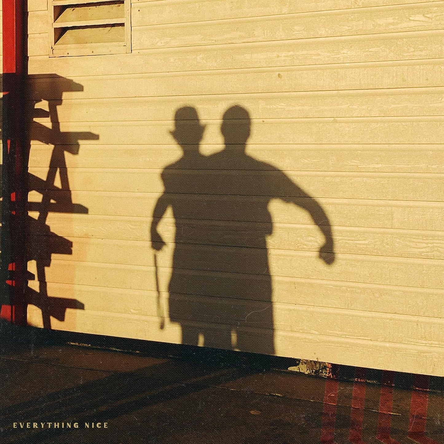 Shadows of two figures with a cane against a textured wall.