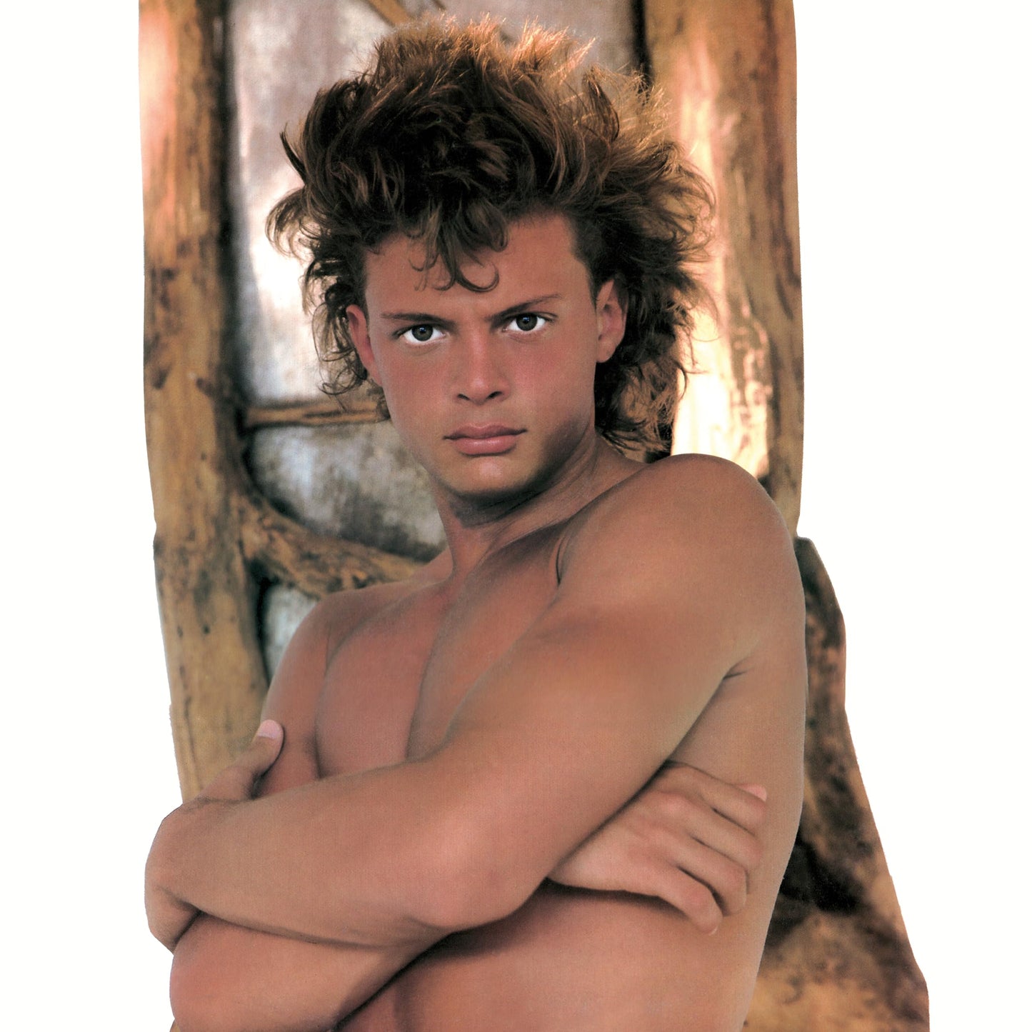 Young man with curly hair and arms crossed, portrait.