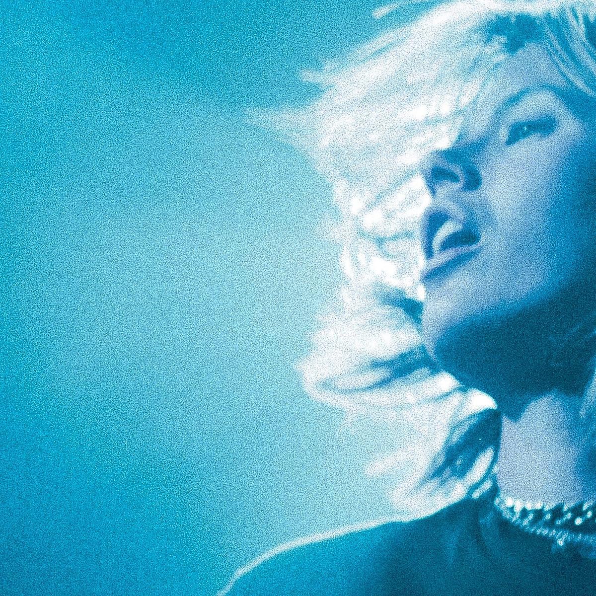 Close-up of a woman’s face in blue, textured, grainy image.