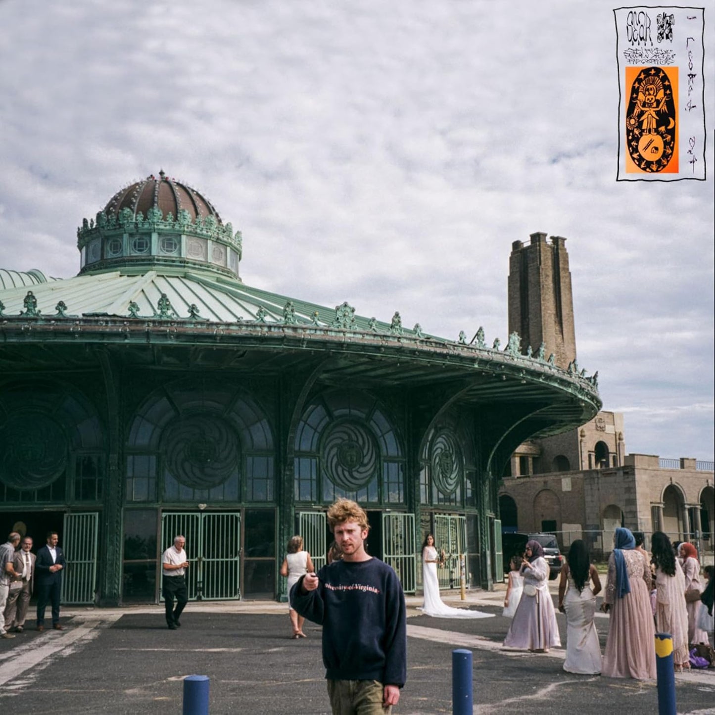 A man stands in front of a green domed building with wedding guests nearby.