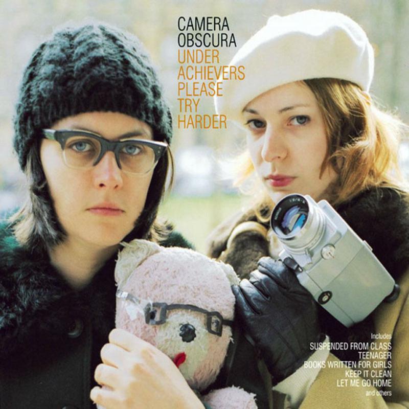 Two women, one with a beanie and one with a beret, holding a camera.