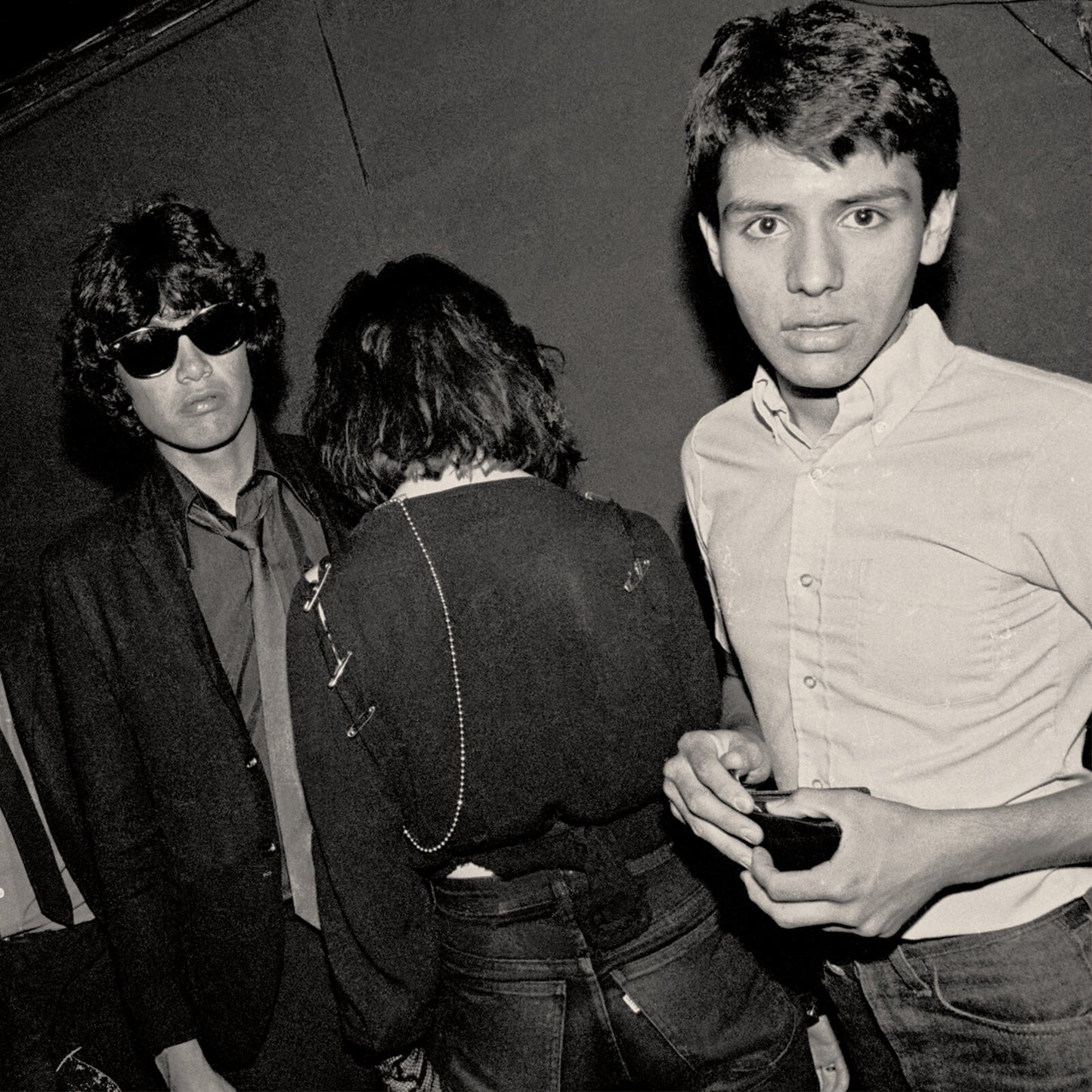 Black and white photo of three young people, two facing camera.