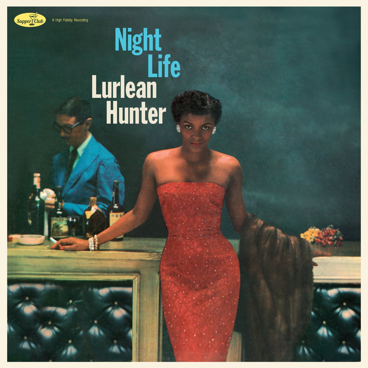 Lurlean Hunter in a red strapless dress stands at a bar with a bartender.