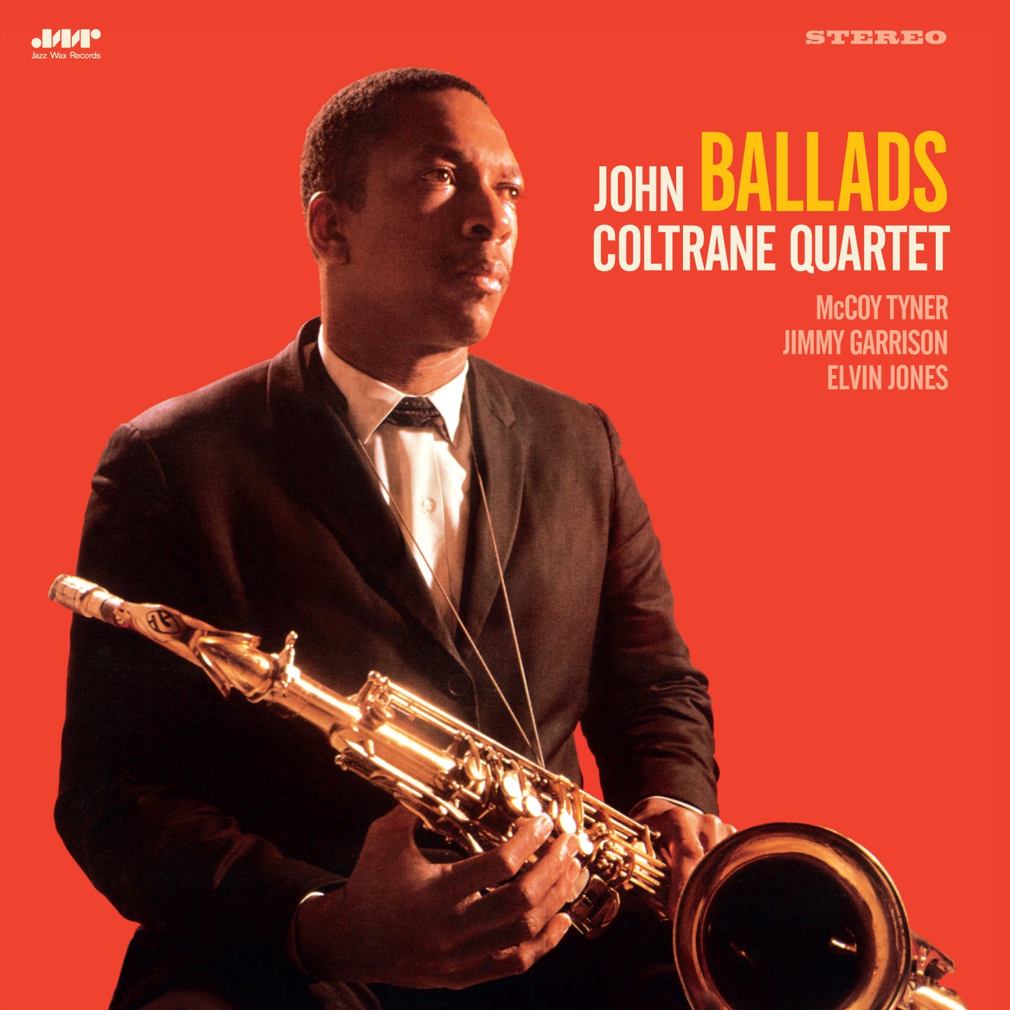 John Coltrane in a suit holding a saxophone against a bright red background.