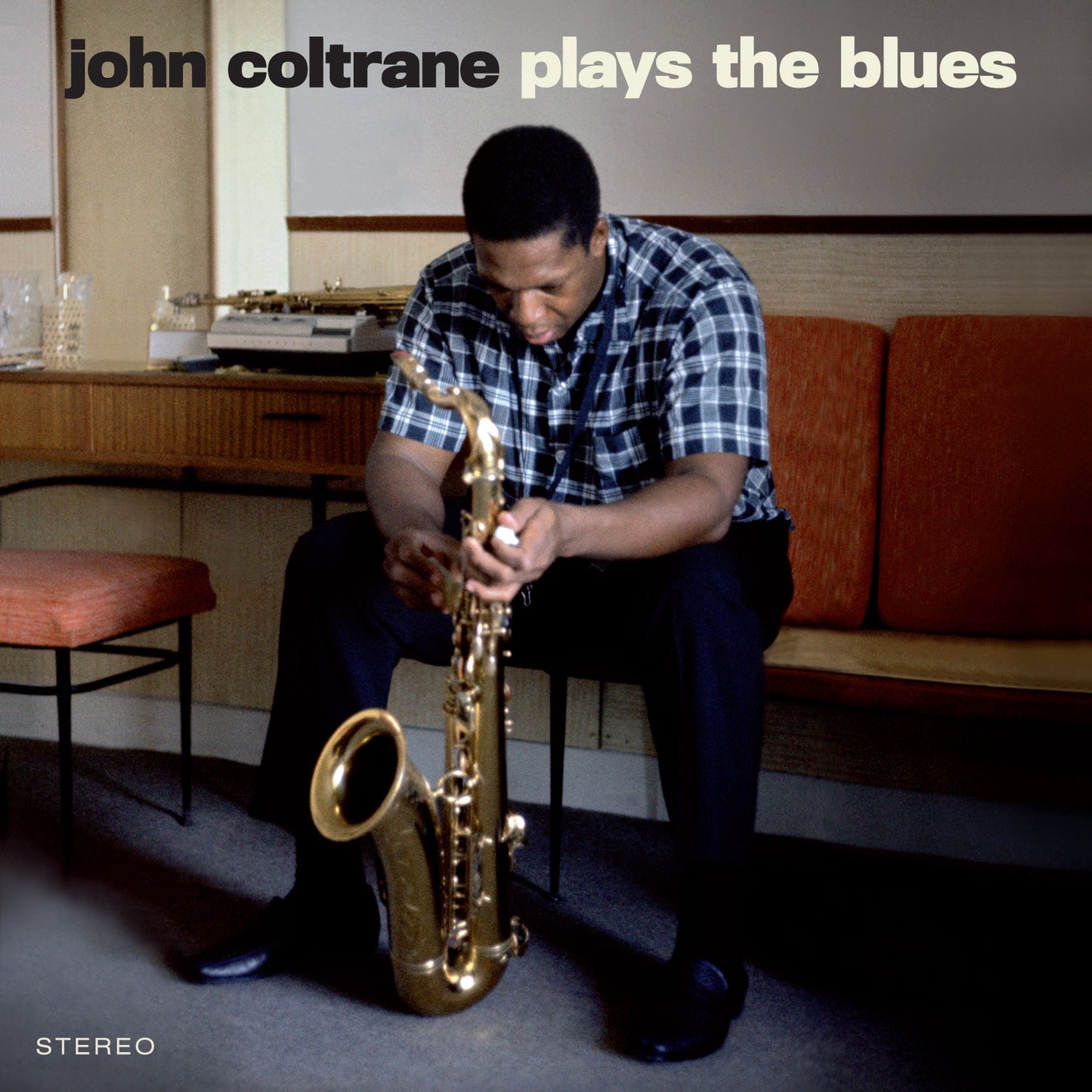 John Coltrane sitting and holding a saxophone, album cover for Plays The Blues.