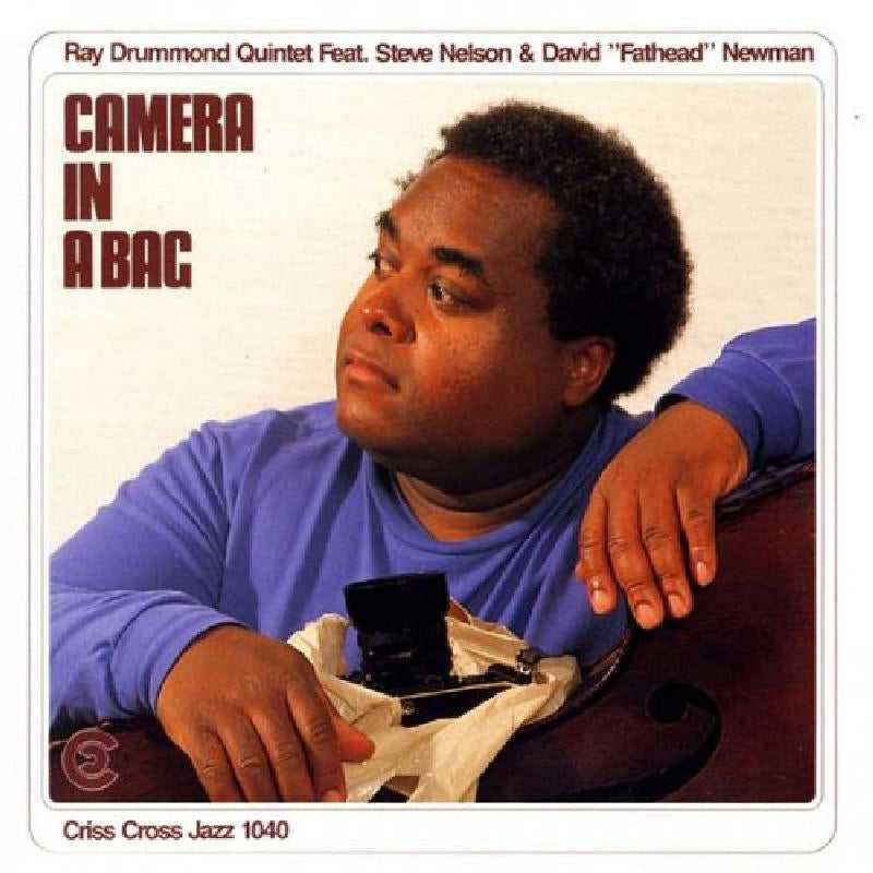 Album cover: Man with bass and camera in a bag.