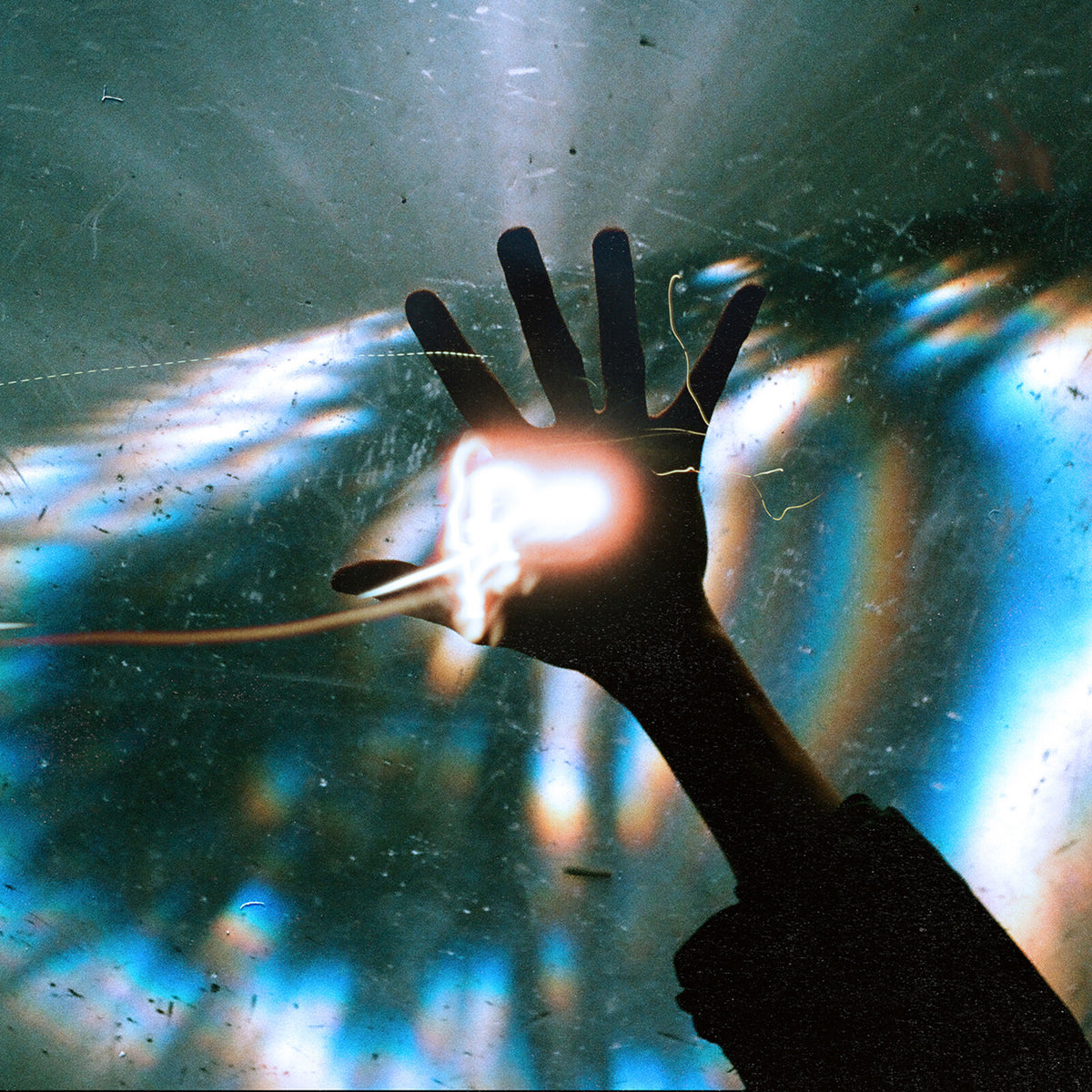 Silhouetted hand reaching towards a bright, swirling light in the sky.