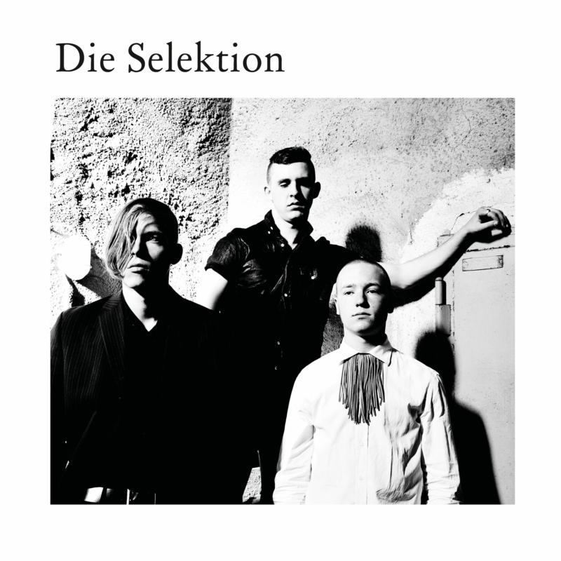 Black and white photo of three men standing against a textured wall.