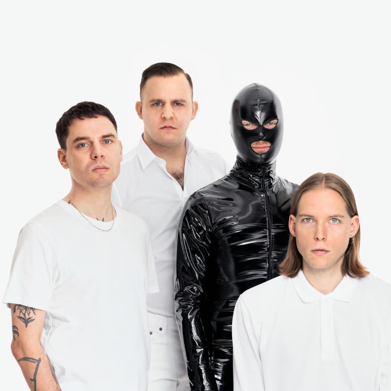 Four men in white shirts, one in a black, shiny, masked suit.