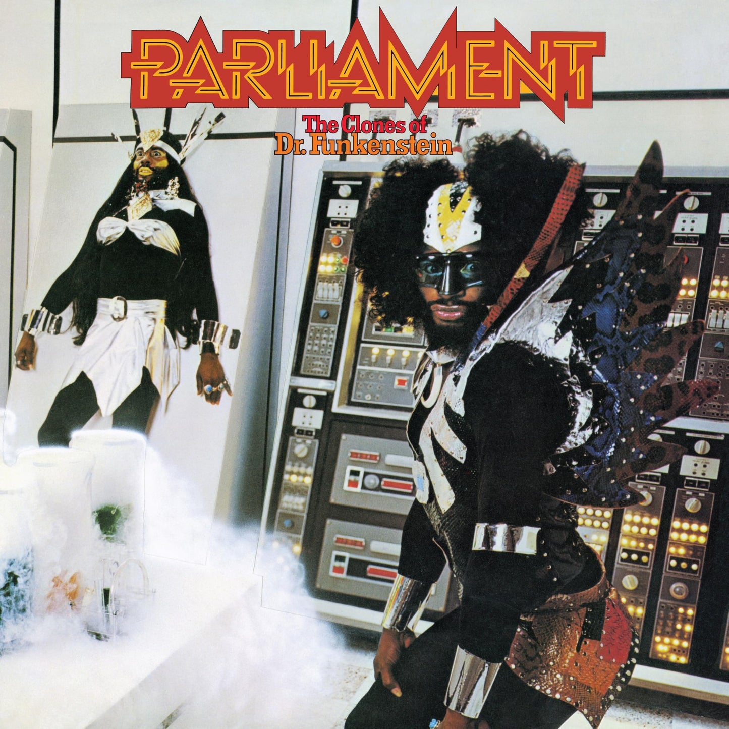 Album cover showing a costumed figure in front of a control panel and poster.