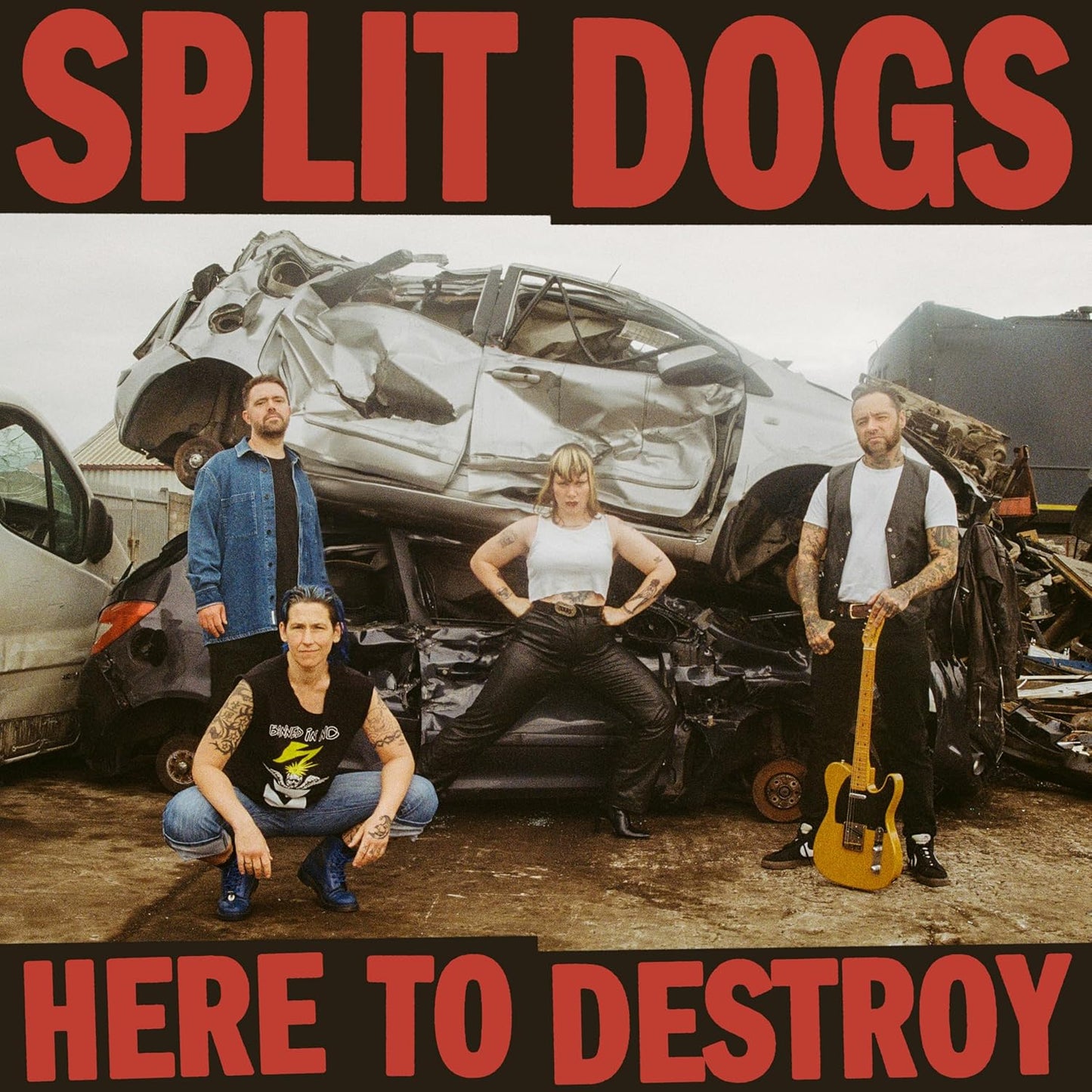 Band Split Dogs posing in front of a severely damaged red car.