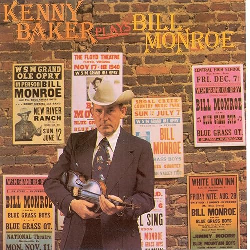 Kenny Baker with violin, surrounded by vintage Bill Monroe concert posters.