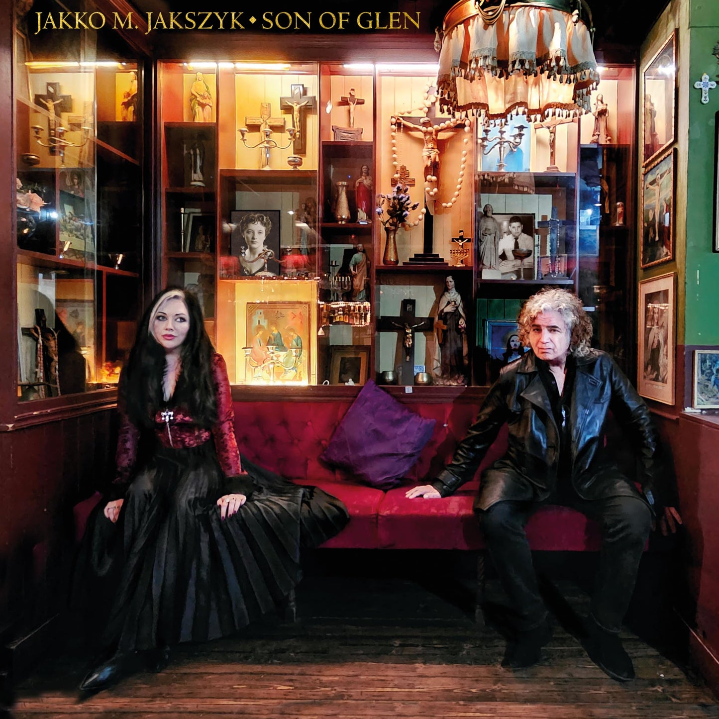 CD cover: two people seated before a cabinet of religious figures.
