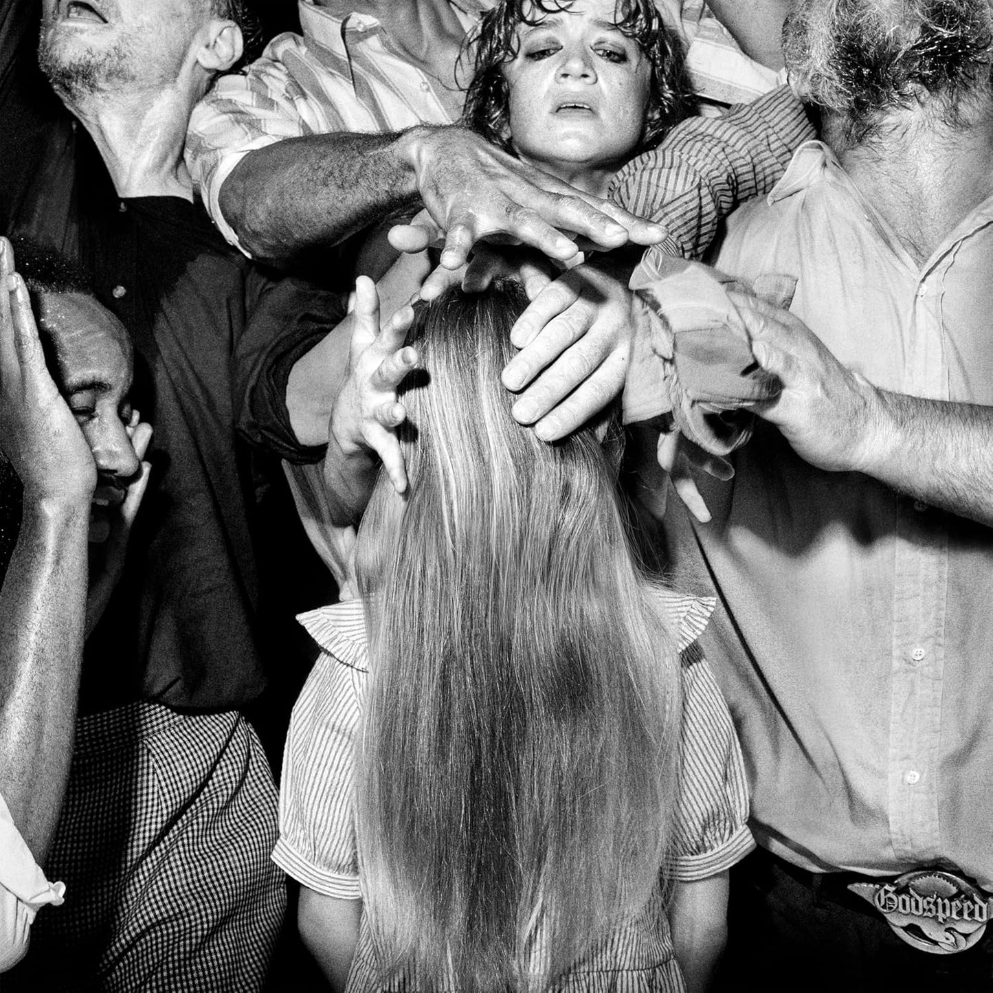 Black and white photo of a woman surrounded by reaching hands.