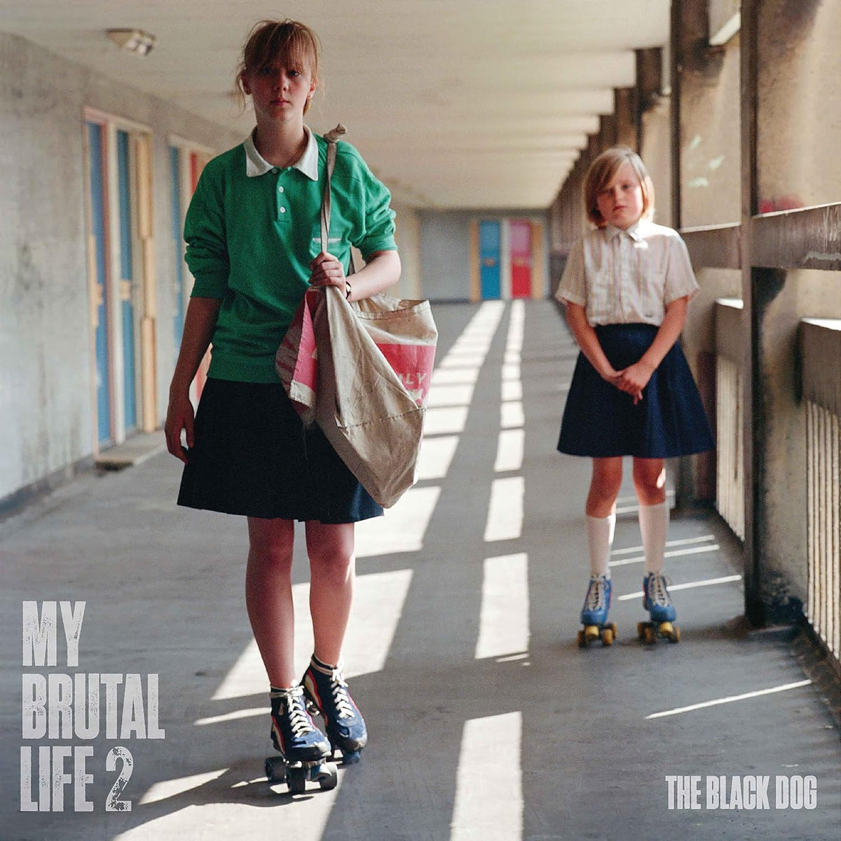 Two girls on roller skates in a school corridor, album cover.
