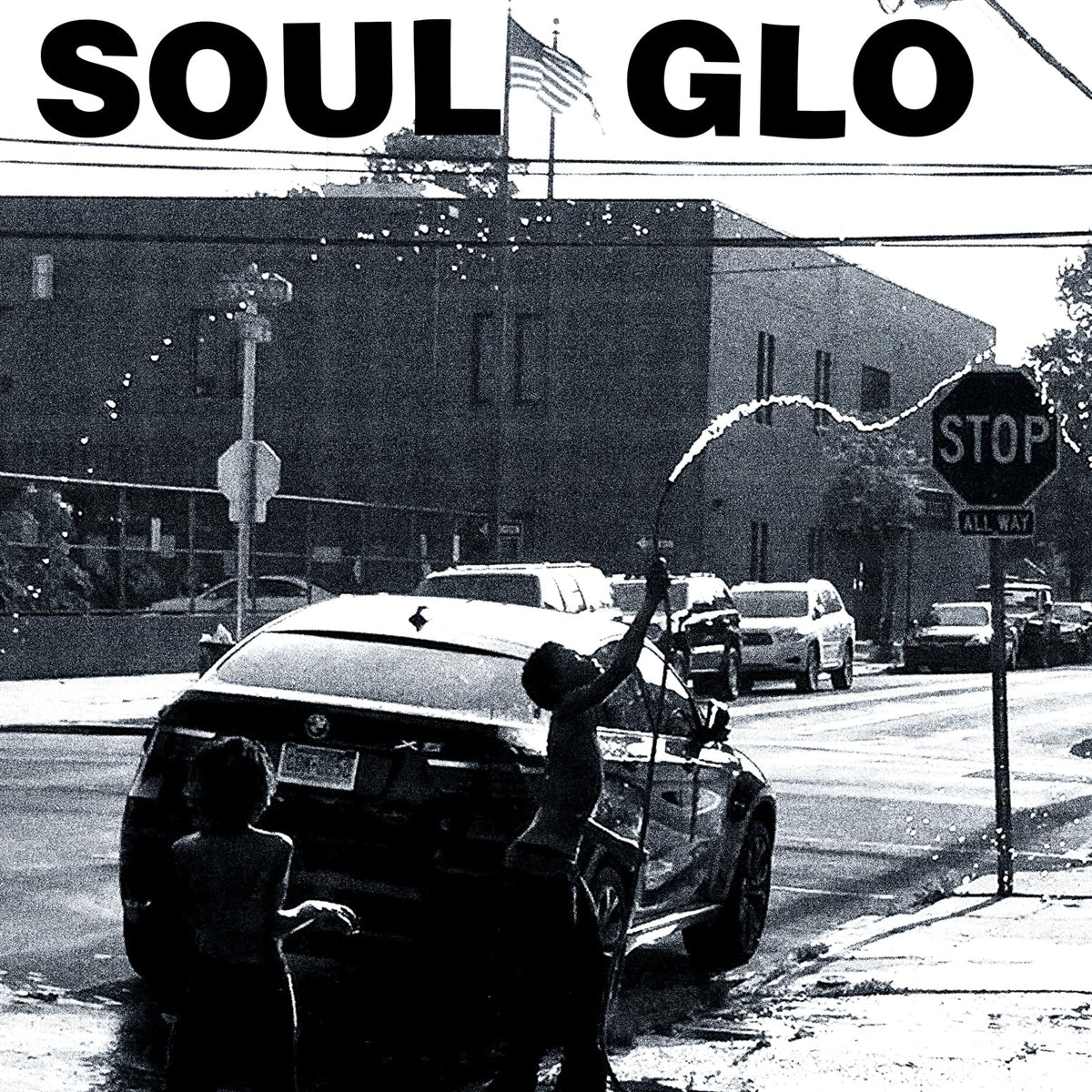 Black and white album cover with a street scene and car.