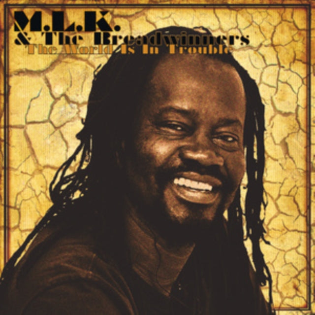 Close-up of a smiling Black man with dreadlocks against a cracked background.