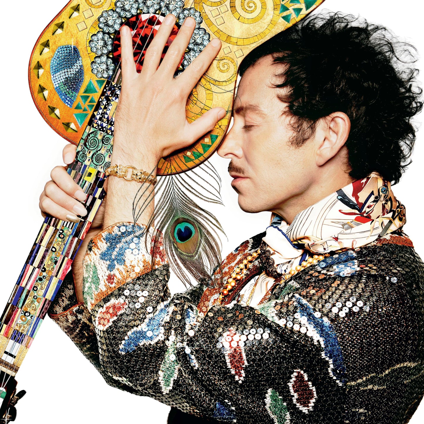 Man with curly hair holding a decorated guitar, peacock feather.