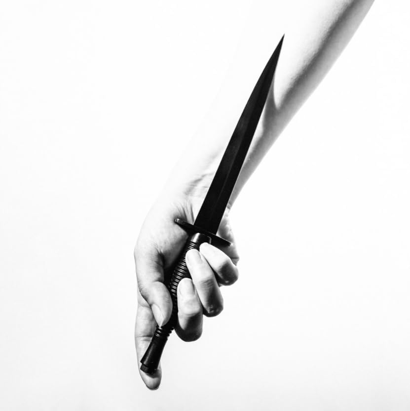 Black and white image of a hand holding a long, pointed dagger.