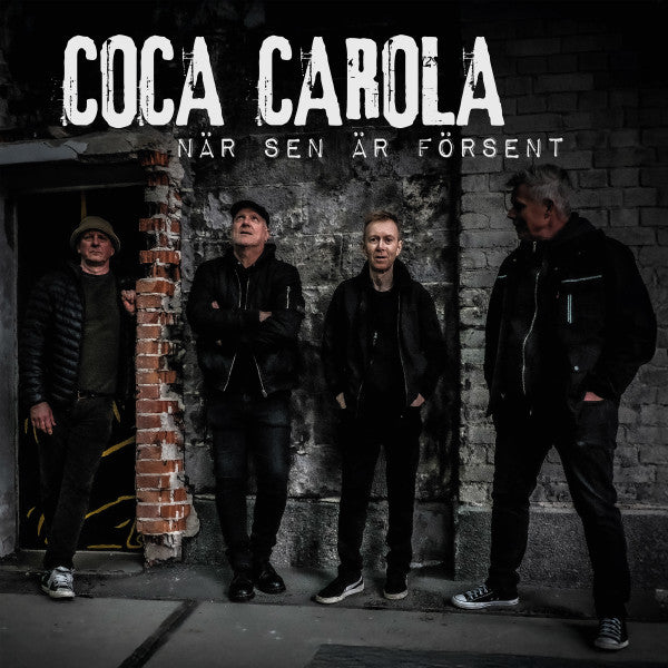CD cover featuring four men in dark clothing standing near a brick wall.