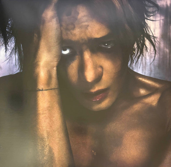 Close-up portrait of a person with intense gaze, obscured by glass.
