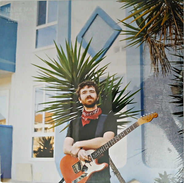 Vinyl record cover featuring a man with a guitar in front of a building.