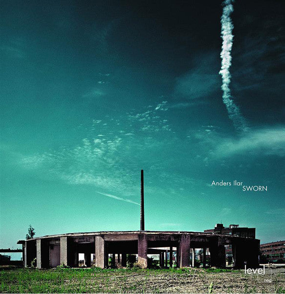 Abandoned industrial building under a cloudy, teal and dark blue sky.