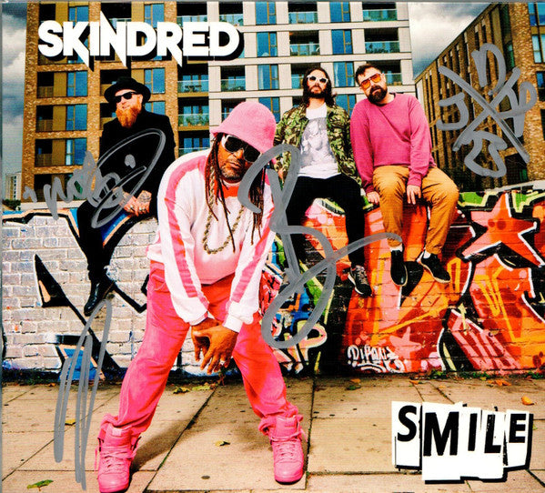 Skindred band members posing in front of a colorful graffiti wall.